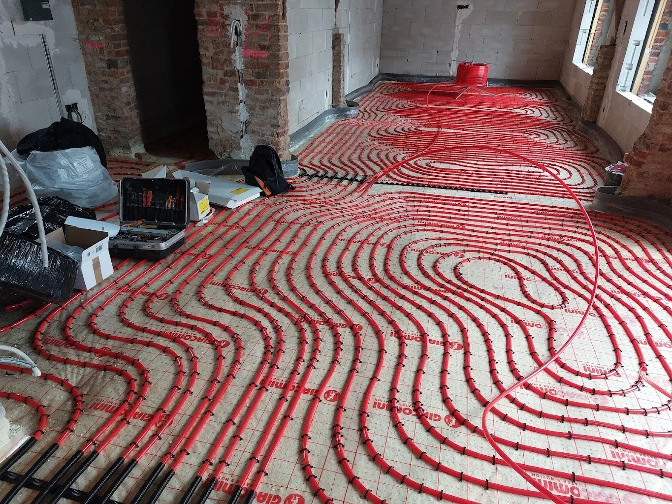 Boucles rouges de plancher chauffant posées sur isolant avant la chape, chantier YR Sanitaire & Chauffage à Tournai