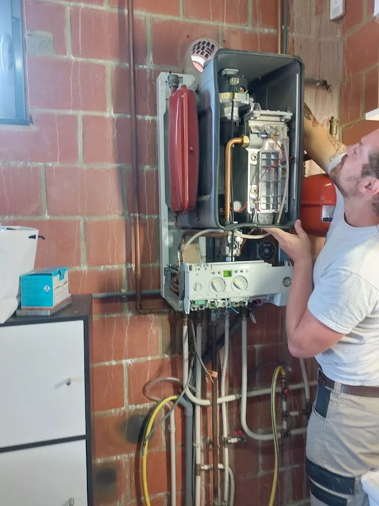 Technicien réalisant l'entretien d'une chaudière murale gaz ouverte, YR Sanitaire & Chauffage à Ath